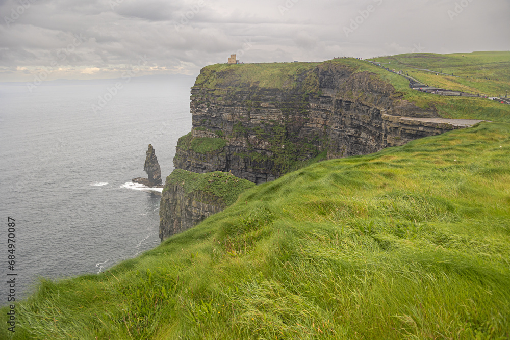 cliffs landscape with castle, green meadow and gray sky in ireland