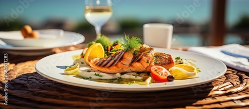 At the spacious restaurant overlooking the sea, a table adorned with black and orange accents showcased a mouthwatering spread of cooked fish, juicy steak, and vibrant lemon slices, offering a