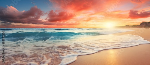 As the sun rises, casting hues of orange and blue across the sky, the tropical beach comes alive with the sound of crashing waves and the sight of gentle sea breeze blending water and sand in a