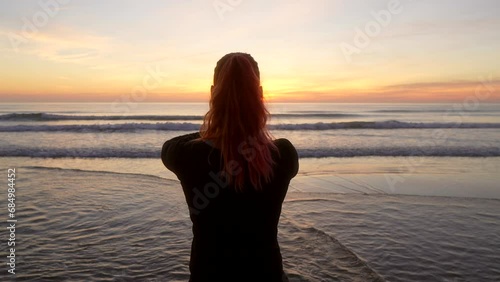 Silhouette of woman doing the tree pose and salute looking towards the sea in slow motion. photo