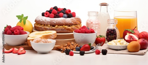 In a beautifully staged photograph, an assortment of healthy breakfast options is displayed on a wooden table against an isolated white background - including a tantalizing cake, freshly baked bread