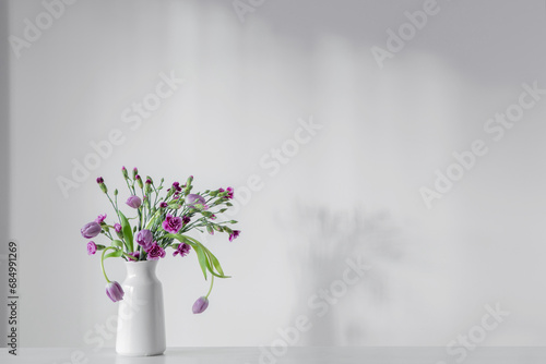 spring purple flowers on white shelf on background wall