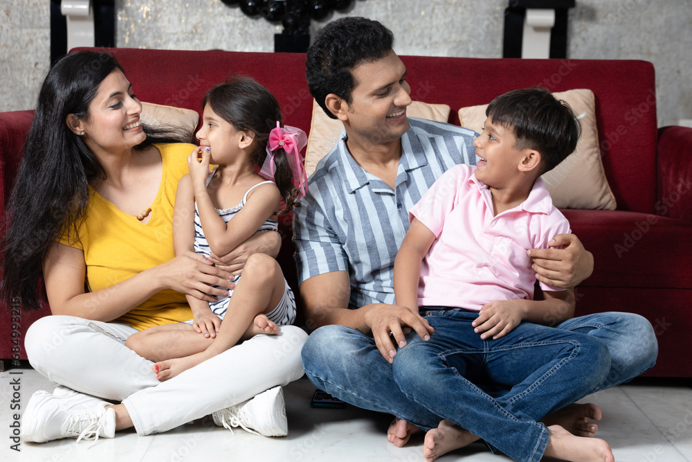 portrait of indian family together sitting on floor in living room looking each other portrait of indian family together sitting on floor in living room looking each other