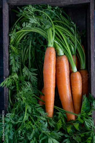 Fresh carrots with leaves on rustic wooden board top view