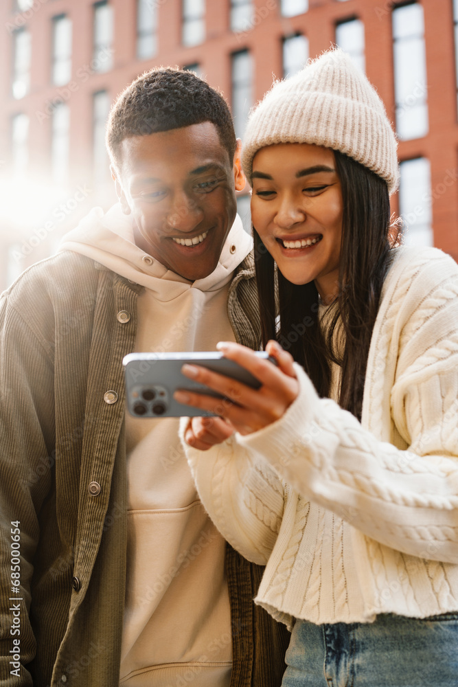 Cheerful couple using mobile phone while standing at street Cheerful couple using mobile phone while standing at street