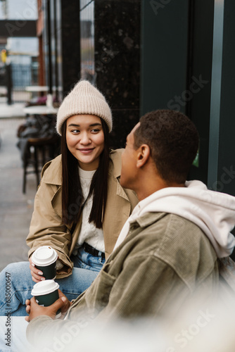 Smiling couple drinking coffee while sitting in cafe outdoors