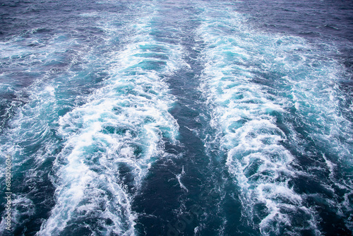 Sea background. The ship's footprint on the water. Waves in the sea. The surface of the sea, bubbling from the screws of the liner. Water foamed by a passing ship. Space for text. Marine texture