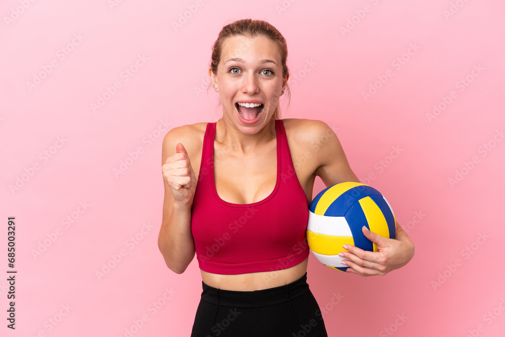 Young caucasian woman playing volleyball isolated on pink background celebrating a victory in winner position Young caucasian woman playing volleyball isolated on pink background celebrating a victory in winner position