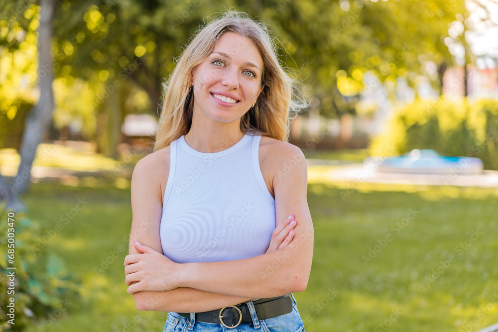 Young blonde woman at outdoors keeping the arms crossed in frontal position