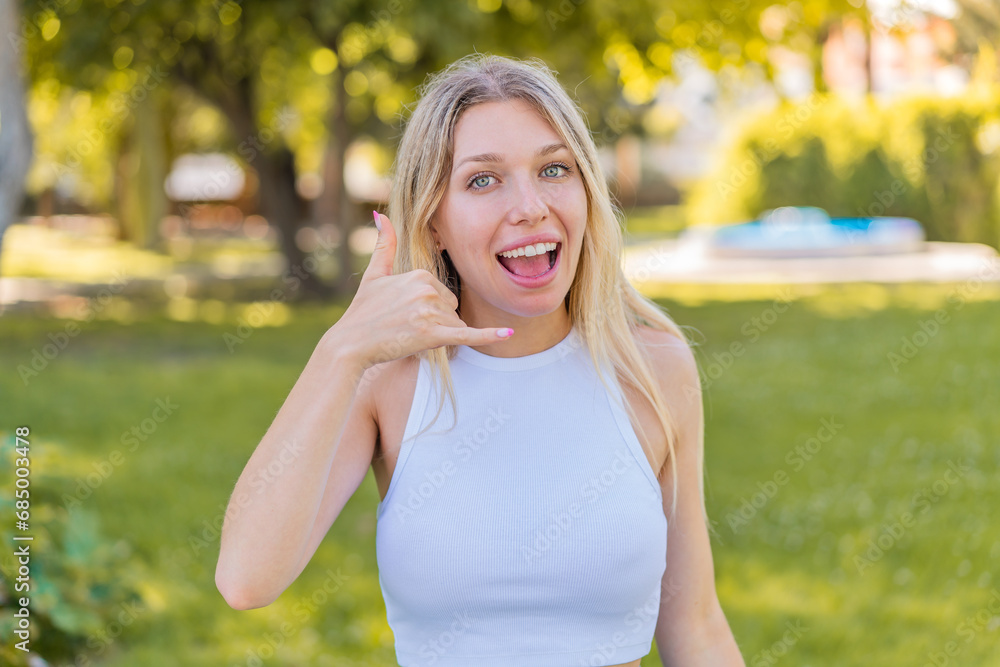 Young blonde woman at outdoors making phone gesture. Call me back sign Young blonde woman at outdoors making phone gesture. Call me back sign