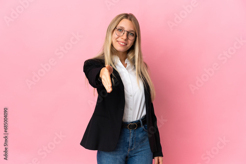 Картината върху платно Business blonde woman isolated on pink background shaking hands for closing a go