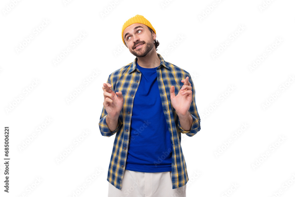 well-groomed authentic young european brunette man with a brutal beard and mustache dressed in a yellow hat and blue shirt