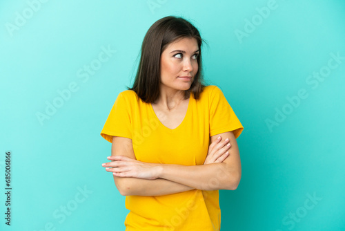 Young caucasian woman isolated on blue background making doubts gesture while lifting the shoulders