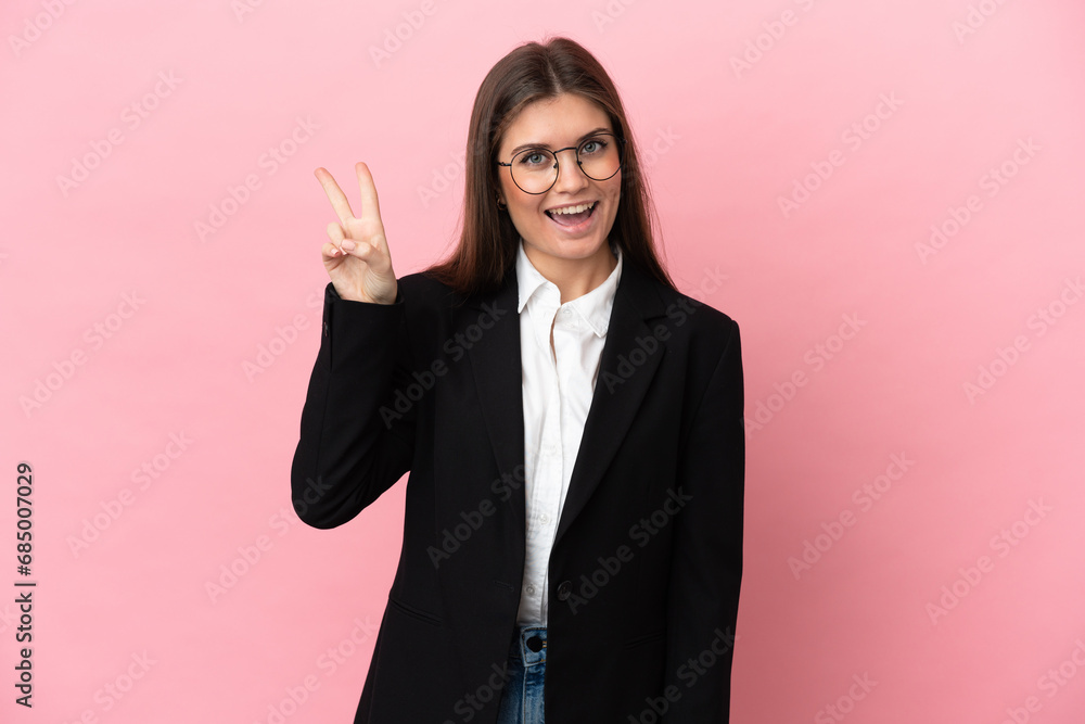 Young Business caucasian woman isolated on pink background smiling and showing victory sign Young Business caucasian woman isolated on pink background smiling and showing victory sign