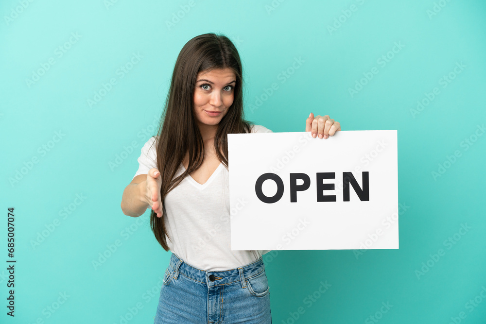 Young caucasian woman isolated on blue background holding a placard with text OPEN making a deal Young caucasian woman isolated on blue background holding a placard with text OPEN making a deal