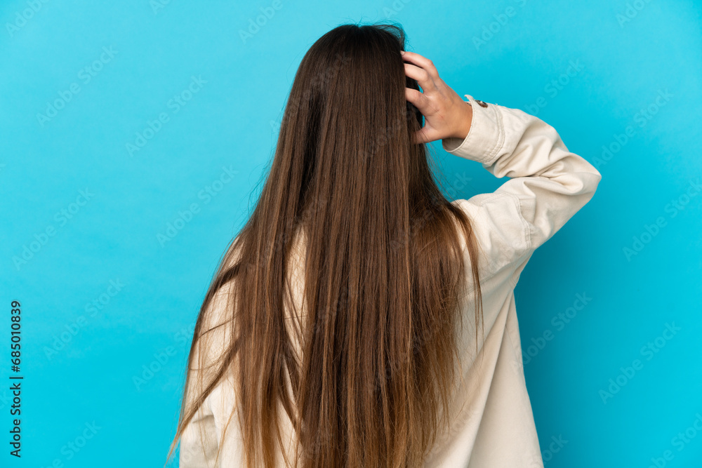 Young caucasian woman isolated on blue background in back position and thinking Young caucasian woman isolated on blue background in back position and thinking