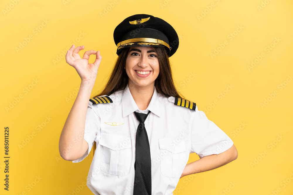 Airplane pilot isolated on yellow background showing ok sign with fingers Airplane pilot isolated on yellow background showing ok sign with fingers