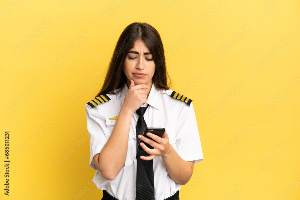 Airplane pilot isolated on yellow background thinking and sending a message Airplane pilot isolated on yellow background thinking and sending a message