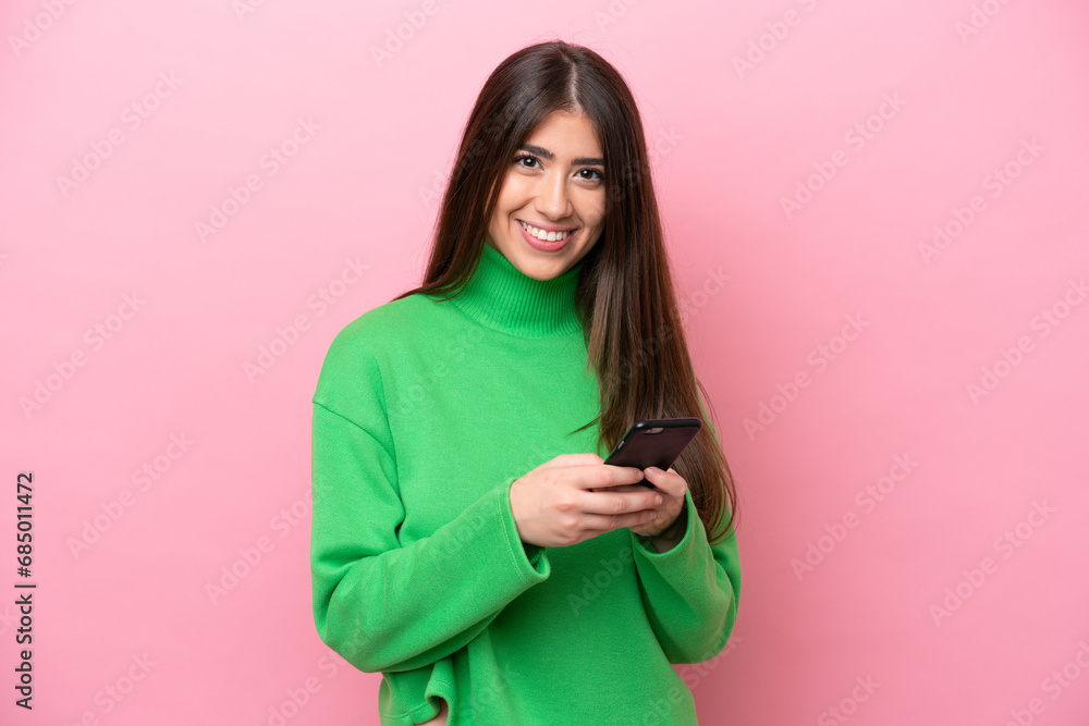 Obraz premium Young caucasian woman isolated on pink background sending a message with the mobile