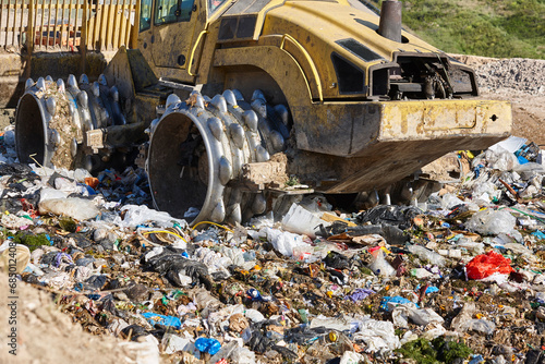 Heavy machinery shredding garbage in an open air landfill. Pollution