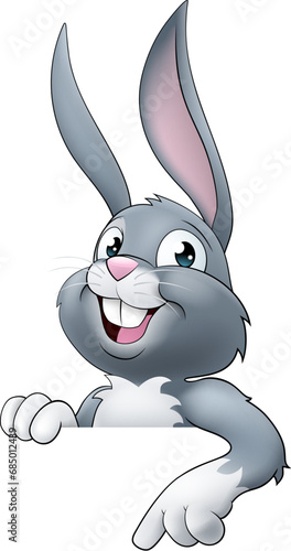 An Easter bunny rabbit cartoon character peeking around a sign