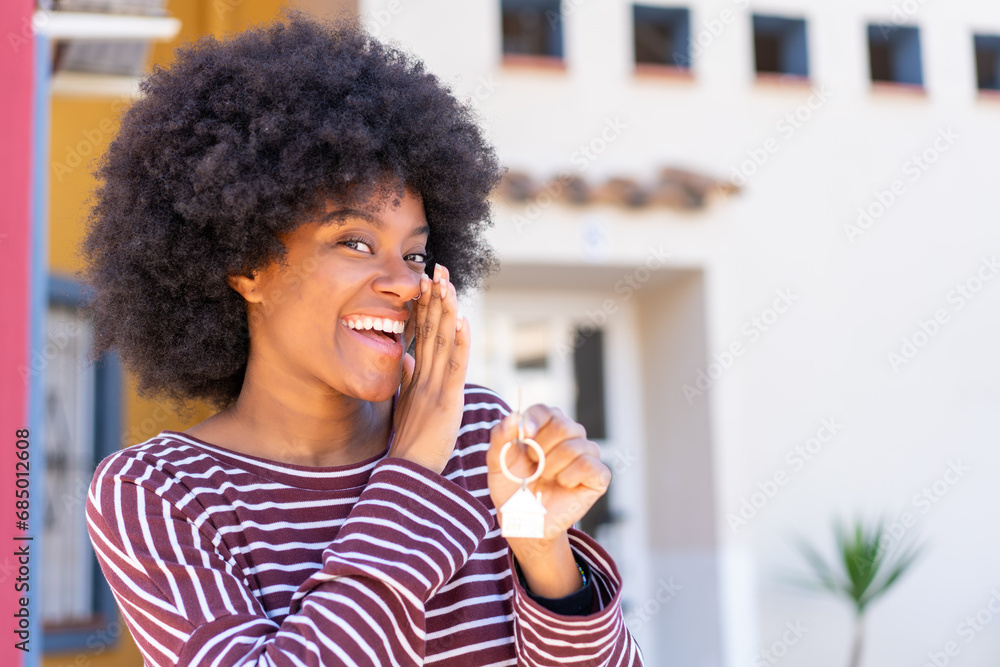 African American girl holding home keys at outdoors whispering something African American girl holding home keys at outdoors whispering something