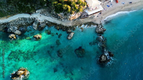 Drone aerial beach view over turquoise crystal clear water, rocky coastline at Greek island's paradise