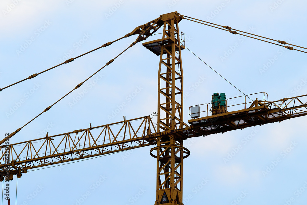 Fragment of a tall construction crane can be seen against a cloudy sky