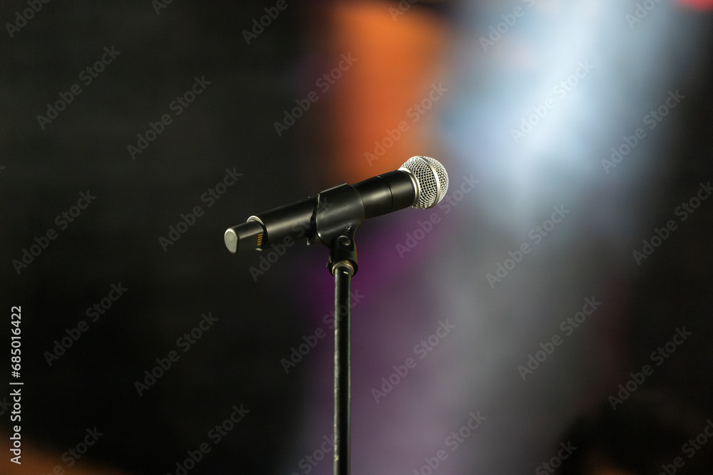 Obraz premium Isolated Microphone with stand on a concert stage with blurred stage lighting background
