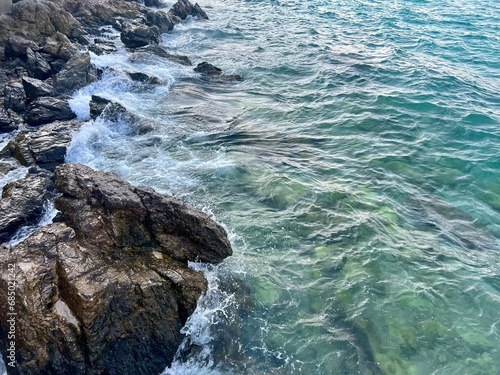 Blue sea and rock. Beautiful sea ​​coast. Coast of the island. Blue sea in winter. Waves crashing on rocks. Seascape on vacation. Blue ocean, white foam and waves. Seaview during travel.