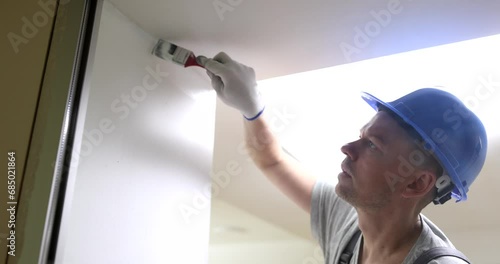 Male builder painting wall white with brush 4k movie slow motion. Finishing work in apartments concept photo