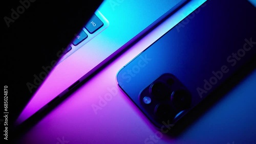 Close up of laptop and smartphone in neon light
