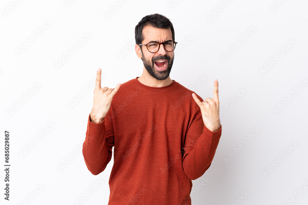 Fototapeta premium Caucasian handsome man with beard over isolated white background making rock gesture