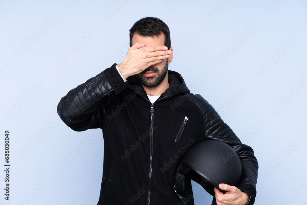 Man with a motorcycle helmet over isolated background covering eyes by hands. Do not want to see something Man with a motorcycle helmet over isolated background covering eyes by hands. Do not want to see something