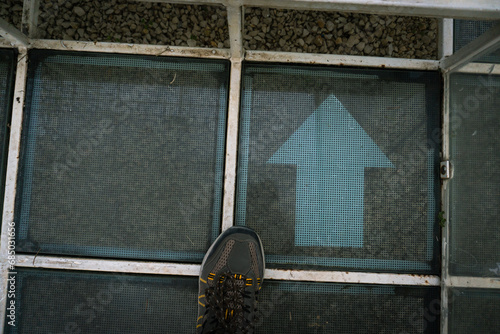Foto astratta di una scarpa vicino una freccia su pannelli geometrici di vetro  photo