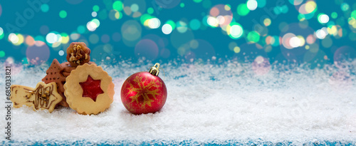 Christmas cookies and red ball on white snow isolated on blue background.