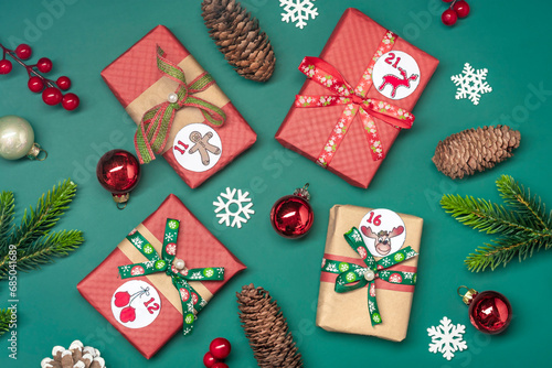 Handmade wrapped red, green gift boxes decorated with ribbons, snowflakes and numbers, Christmas decorations and decor on green table Xmas advent calendar concept Top view Flat lay Holiday card