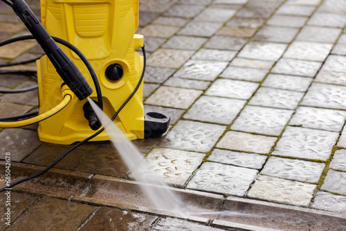 Washing Service of Pavement Paving Stones. High Pressure Cleaning Street Road. Clean Concrete Gutter on Floor of Garden with Karcher. photo