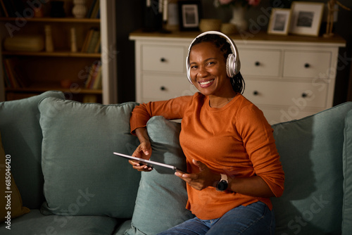 Woman with headphones using tablet computer while relaxing at home