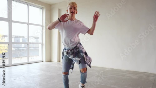 Laughing young man dancer in casual dancing in front of wall. People emotions lifestyle concept. Mock up copy space.
