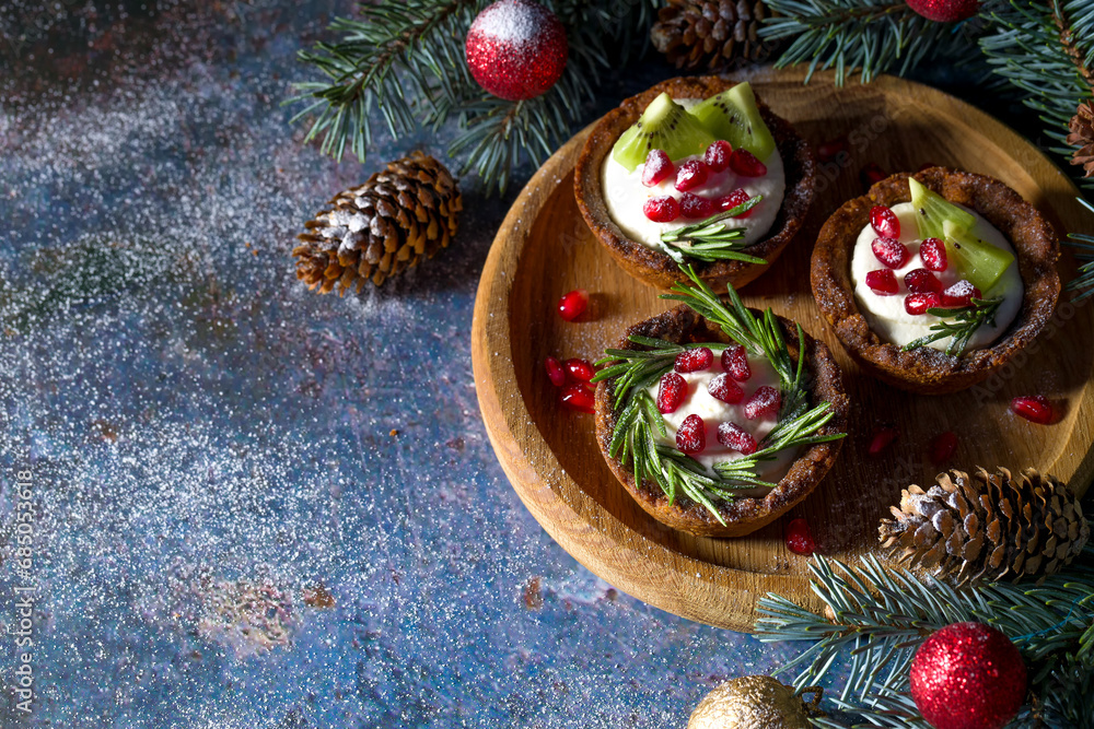 Christmas nut tartlets. Delicious, beautiful cupcakes are decorated with Christmas garlands and Christmas tree branches. Selective focus. Copy space Christmas nut tartlets. Delicious, beautiful cupcakes are decorated with Christmas garlands and Christmas tree branches. Selective focus. Copy space