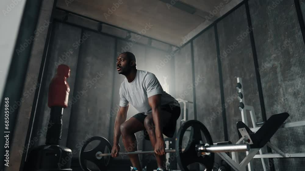 Man doing squats with barbell in hands. African american guy exercising squat holding barbell with big weight in gym. Sport powerlifting training workout healthy lifestyle make athletic body concept. Man doing squats with barbell in hands. African american guy exercising squat holding barbell with big weight in gym. Sport powerlifting training workout healthy lifestyle make athletic body concept.