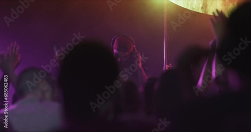 Crowd hands, dancing and nightclub DJ in rave, techno or disco lights for music, party and celebration or festival event. Group of people or audience on club dance floor for cheers or energy in dark photo