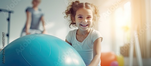 Girl receiving physiotherapy in a children s therapy center doing exercises on a gymnastic ball with physiotherapists for scoliosis prevention and treatment copy space image photo