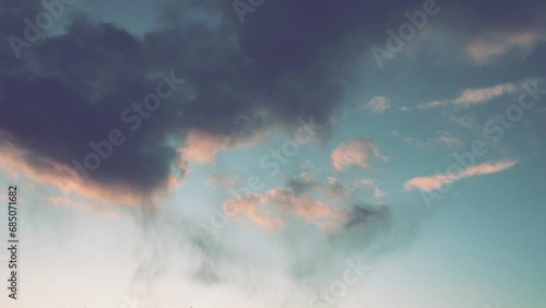 Atmosphere, weather during sunset or sunrise. Pink and dark clouds timelapse. Cumulus clouds. Climate forecast. An interestingly shaped cloud floats quickly across the sky. Volumetric light effect. photo