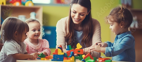 Kindergarten teacher supervising play with colorful wooden educational toys copy space image photo