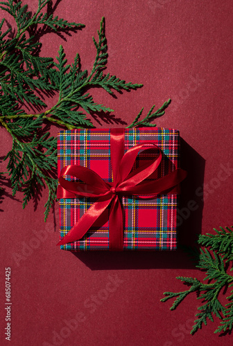 Christmas concept composition with tartan pattern gift box on the red background. Winter holiday greeting card.