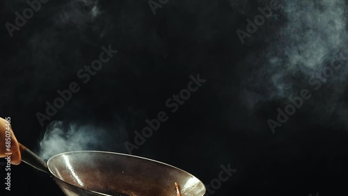 Man holding wok pan and frying colorful sweet peppers against black background. Wok noodles ingredients preparation. Concept of Asian food, cuisine, restaurant, taste, cooking, recipe photo