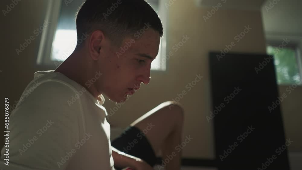 Exhausted man athlete rubs wet hair with hand sitting on floor in club for fighting sports. Rest after active movements. Sweat dripping from forehead and feeling tired after workout Exhausted man athlete rubs wet hair with hand sitting on floor in club for fighting sports. Rest after active movements. Sweat dripping from forehead and feeling tired after workout