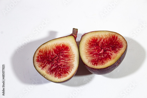 two pieces of figs with a bright and fresh dark red color. served on a plain white background